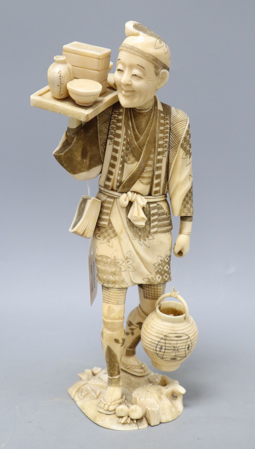 A Japanese Meiji walrus ivory figure of a tradesman, height 32cm